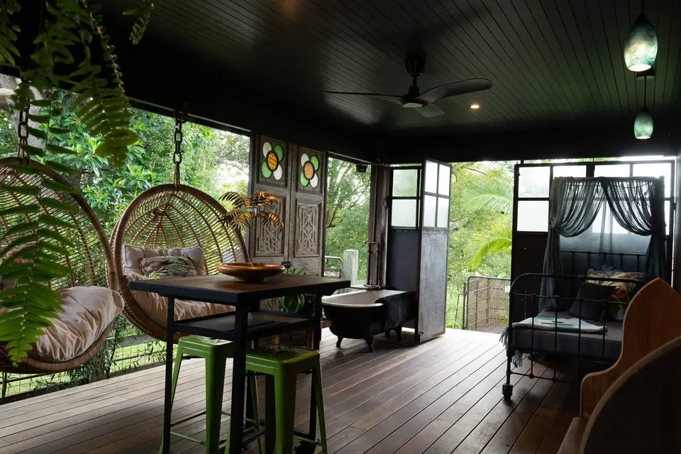 The Barnita covered deck with hanging chairs, a daybed and an antique bathtub