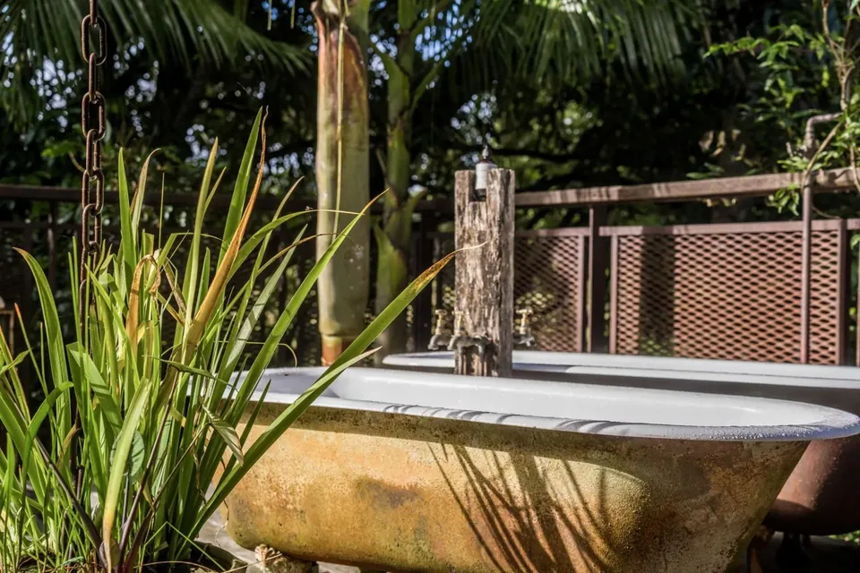An outdoor claw-foot tub on the barn deck surrounded by grasses