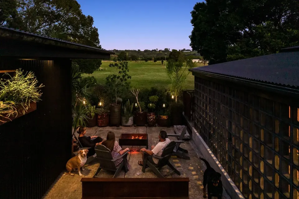 The fire pit glowing at night with the barn lit warmly behind